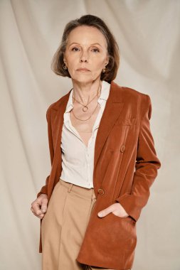 A vibrant woman in an orange blazer and tan pants strikes poses. clipart