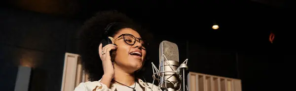 stock image A female vocalist passionately sings into a microphone in a professional recording studio during a music band rehearsal.
