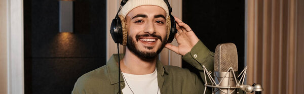 Человек в шляпе страстно поет в микрофон во время репетиции музыкальной группы в студии звукозаписи.