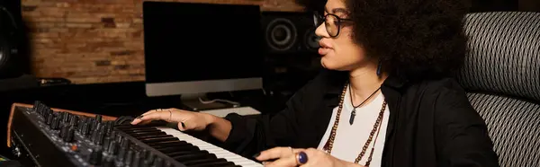 stock image A woman with glasses passionately playing the keyboard in a recording studio during a music band rehearsal.