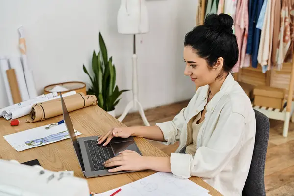 stock image Woman in casual clothes redesigning garments on laptop.