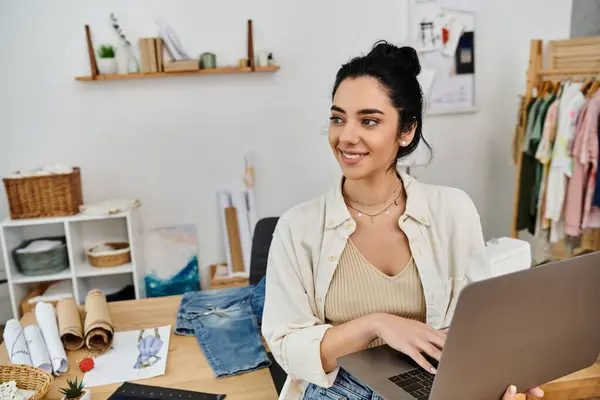 stock image A young woman transforms her clothes while seated with a laptop.