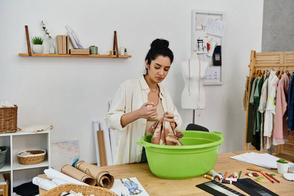 A young woman in casual attire upcycling clothes in a green basin.