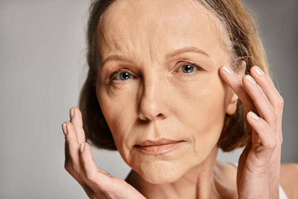 Зрелая, привлекательная женщина в удобной одежде, выражающая эмоции, кладущая руки на лицо.