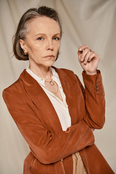 Older woman in tan jacket striking a graceful pose for a photo.