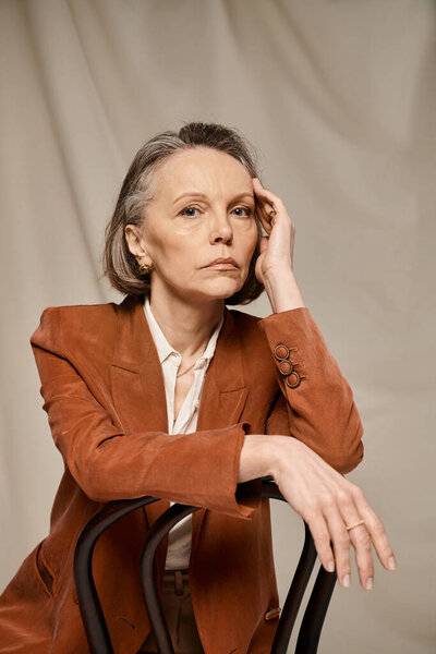 Пожилая женщина изящно сидит на стуле, занимаясь нежными упражнениями и созерцанием.