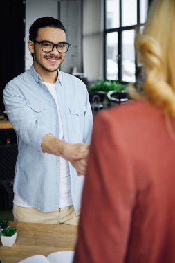 Bir erkek ve kadın ofis ortamında el sıkışıyor..