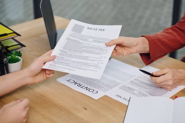 A man hands a resume to a woman during a job interview. clipart