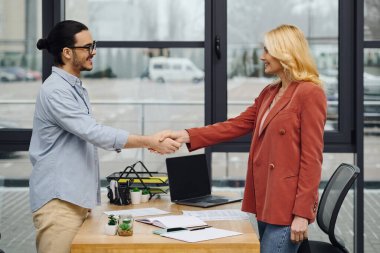 Bir erkek ve kadın ofis ortamında el sıkışıyor..