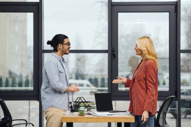 A man and woman are talking in an office. clipart