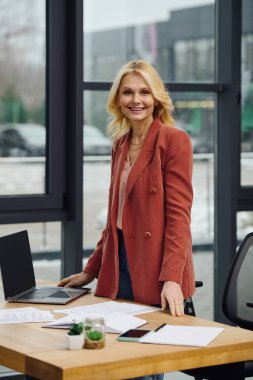 A woman focuses, standing at a desk with laptop. clipart