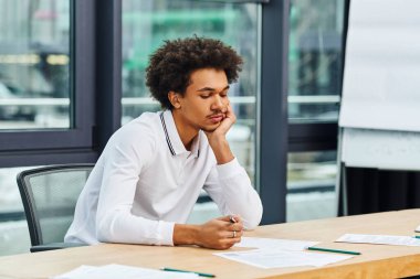 A man attentively sitting at desk in office. clipart