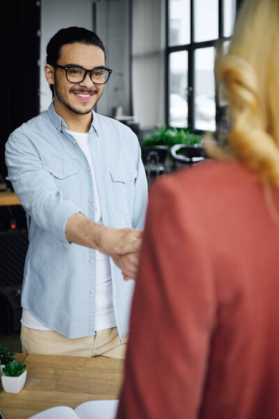 Мужчина и женщина пожимают руку в офисе.