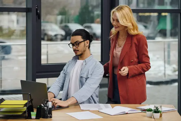 stock image Man and woman working on a laptop in an office.