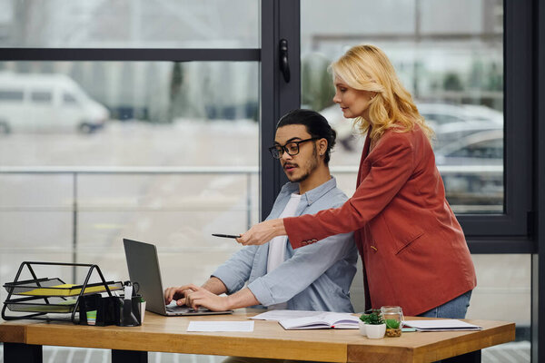 Мужчина и женщина сосредоточены на ноутбуке в офисе.