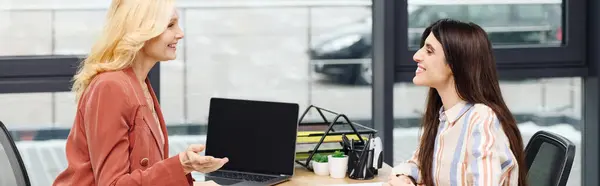 stock image Two businesswomen engaging in a discussion at an office table.