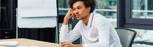 A young man sits at a desk in an office, focused and determined.