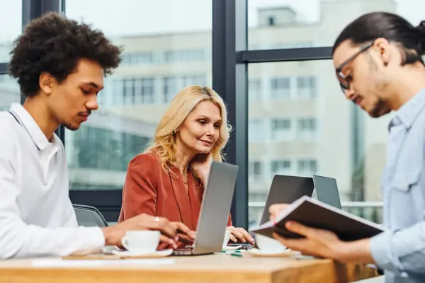 stock image Job seekers focus on laptops during group interview at round table.