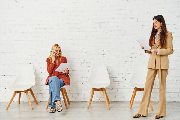 Two women engaged in conversation while sitting in chairs.