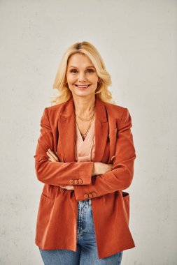 Şık giyinmiş şık bir kadın kameraya rahatça poz veriyor.
