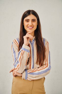 Stylish woman in striped shirt and tan pants posing for a portrait. clipart