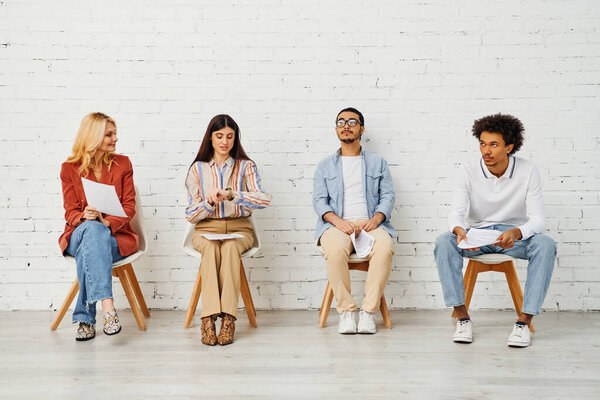 A diverse group of people seated in a row against a brick wall.