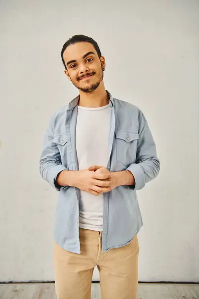 stock image A young man in a blue shirt and tan pants poses confidently.