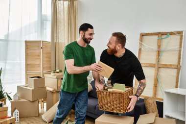 Two men, a gay couple in love, stand side by side in a room surrounded by boxes, starting a new life in their new home. clipart