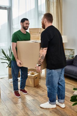 Gay couple in love, surrounded by boxes, savor the moment as they stand next to each other in their new living room. clipart