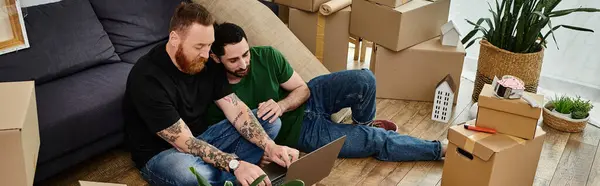 stock image Couple of men, immersed in work, surrounded by moving boxes, showcasing dedication and focus.