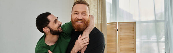 Бородатый мужчина нежно обнимает партнера в своем новом доме, символизируя любовь и новое начало.