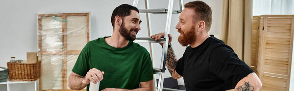 Глубоко влюбленная гей-пара стоит бок о бок, держа лестницу в своем новом доме, вместе открывая новую главу.