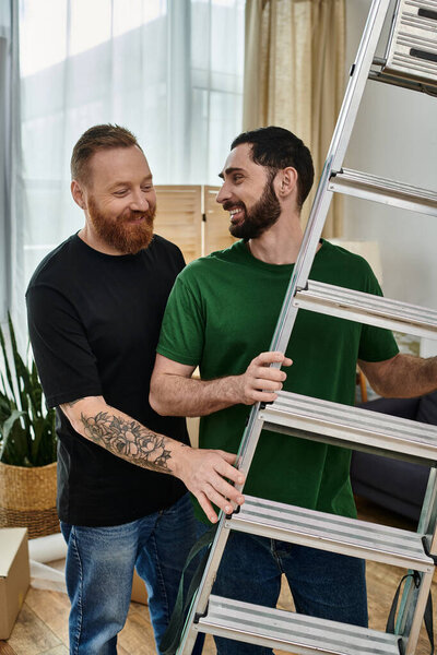 A gay couple, united in love, stand together near a ladder, embarking on a new beginning in their new home.