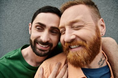 Gri bir duvara karşı sevgi ve ahenk saçan, günlük giysiler içinde eşcinsel bir çift..