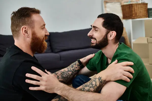 stock image A gay couple in love sits together on stacked boxes, symbolizing a new chapter in their lives