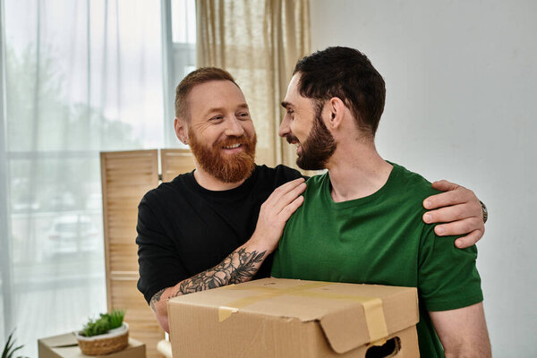 A gay couple in love, moving into their new home, stand side by side holding a box, ready for their new life together.