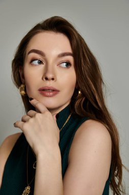 Yeşil elbiseli şık, hamile bir kadın portre için kendine güvenen bir poz veriyor..