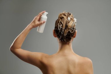 Entelektüel kadın saç bakım ürünleri uyguluyor ve saç yıkıyor..