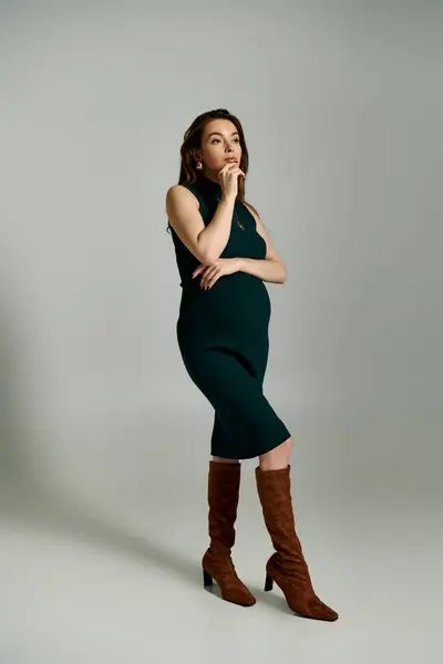 stock image A young pregnant woman exudes elegance in a vibrant green dress as she poses for a portrait.