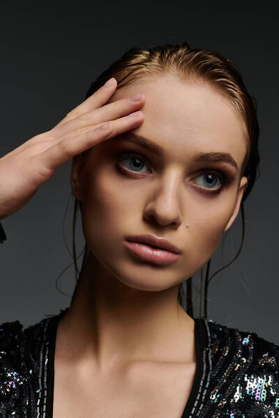 Женщина с очаровательными голубыми глазами в гладком черном топе, демонстрирующая свои мокрые волосы.