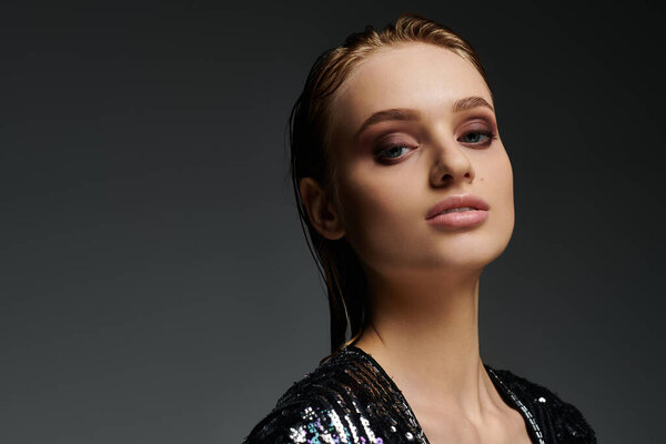 Женщина в блестящем платье элегантно позирует.