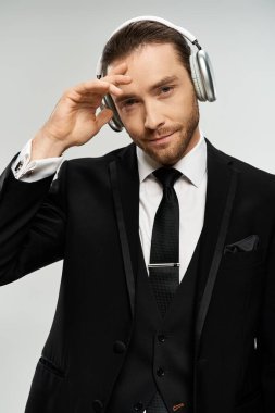 Takım elbiseli yakışıklı bir iş adamı stüdyo ortamında kulaklıkla müzik dinliyor..