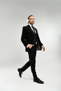 Bearded businessman in a sleek suit, wearing headphones, strolling confidently. clipart