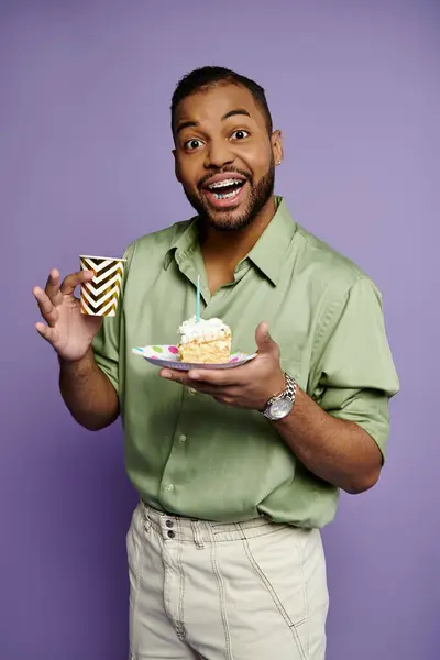 stock image Young African American man with braces smiling while holding a plate with a delicious piece of cake.