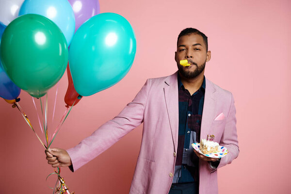 A young African American man in braces holding a plate of cake and balloons, smiling in celebration on a pink background.