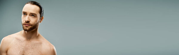 A bearded, shirtless man strikes a pose in a studio setting against a grey background.