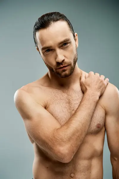 stock image A bearded, shirtless man striking a pose against a neutral grey backdrop in a studio setting.