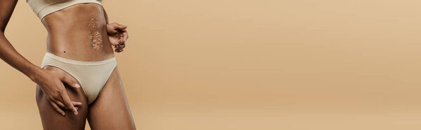 A stunning African American woman showcases her physique in a white bikini against a beige backdrop.