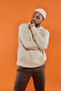 Canlı turuncu arka planda poz veren şık Afrikalı Amerikalı bir adam..