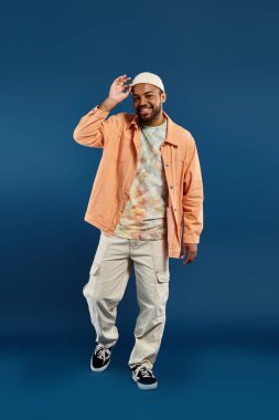 Şık bir Afro-Amerikan erkek canlı mavi bir arkaplanda poz veriyor..